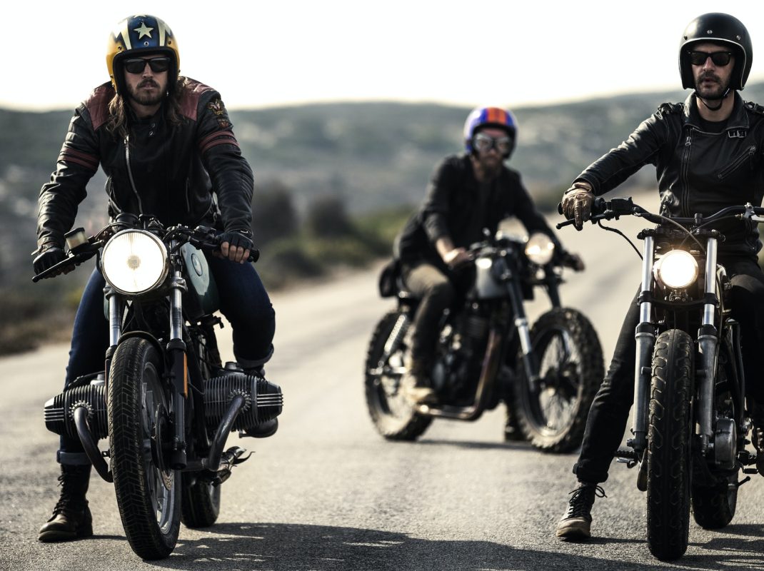 three-men-wearing-open-face-crash-helmets-and-goggles-sitting-on-cafe-racer-motorcycles-on-a-rural.jpg three-men-wearing-open-face-crash-helmets-and-goggles-sitting-on-cafe-racer-motorcycles-on-a-rural.jpg